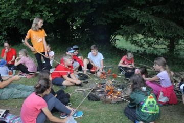 Děti u táboráku si opékají špekáčky